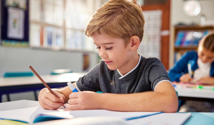 Child writing in notebook at primary school
