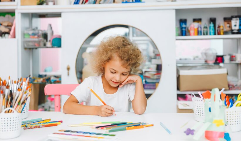 Cute little blonde preschooler girl draws at home