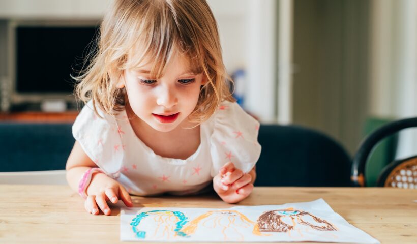 female child indoor drawing on a paper