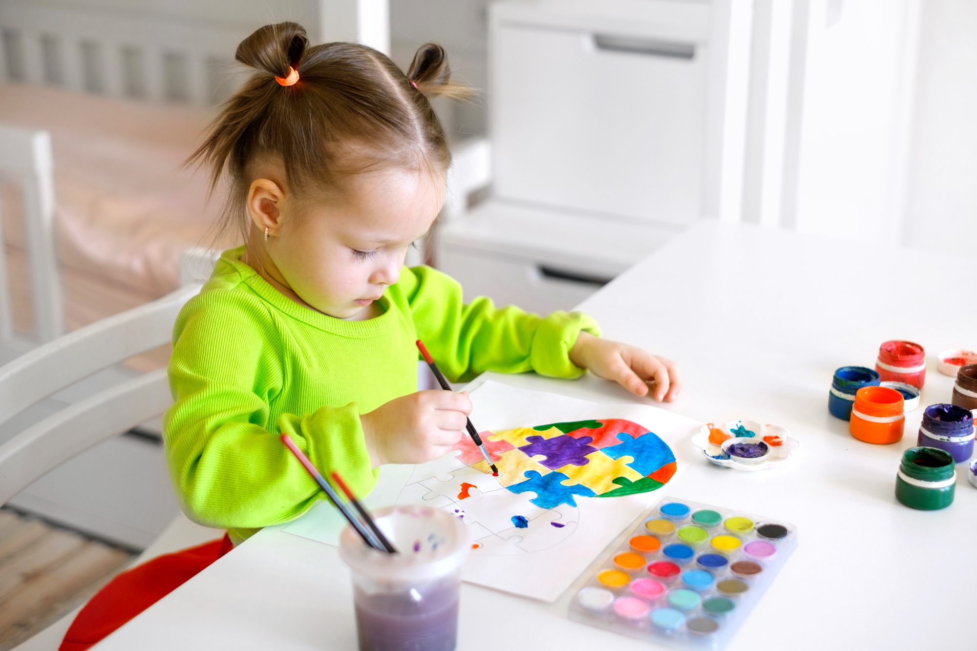 Kid is concentrating on coloring the puzzle inside heart with different colors